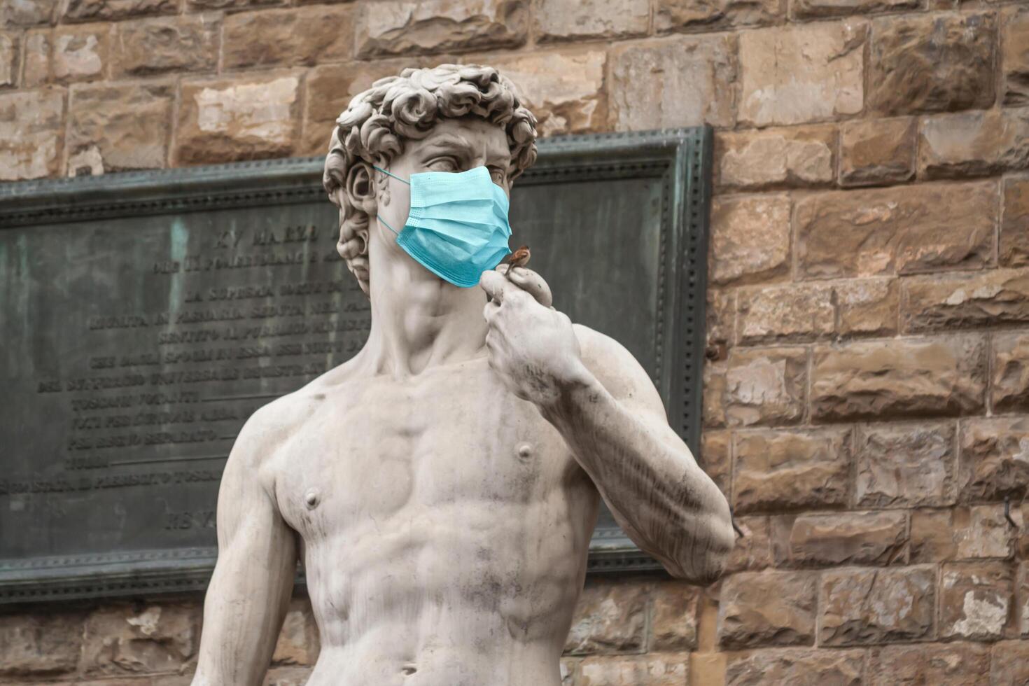 la statue de david sur la piazza della signoria en italie portant un masque médical de protection bleu photo