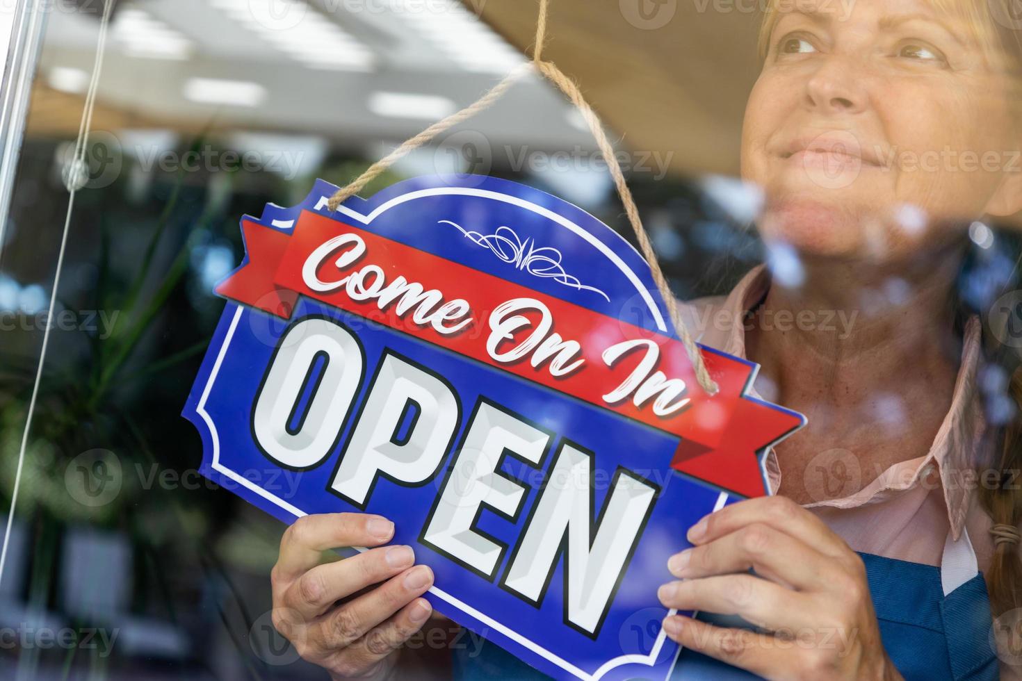 heureuse femme propriétaire d'un magasin tournant une fenêtre ouverte photo