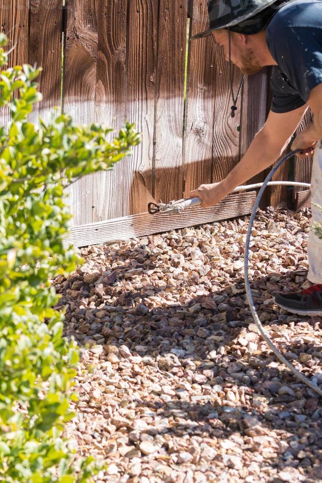 peintre professionnel pulvérisant une clôture de jardin avec tache photo