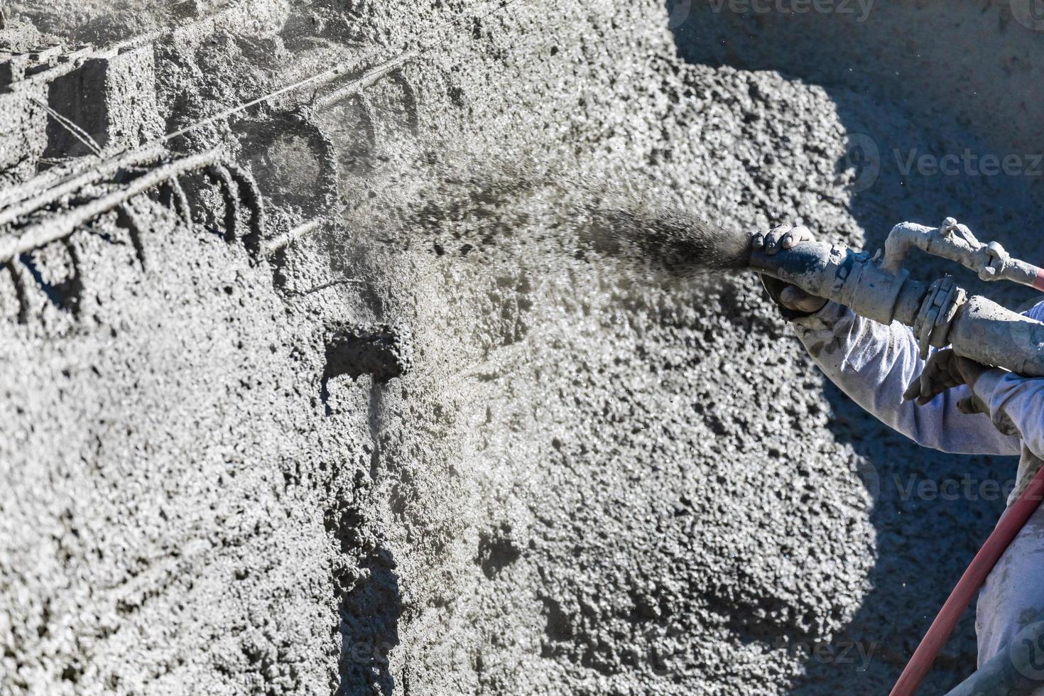 ouvrier en construction de piscine tirant sur du béton, du béton projeté ou de la gunite à travers un tuyau photo