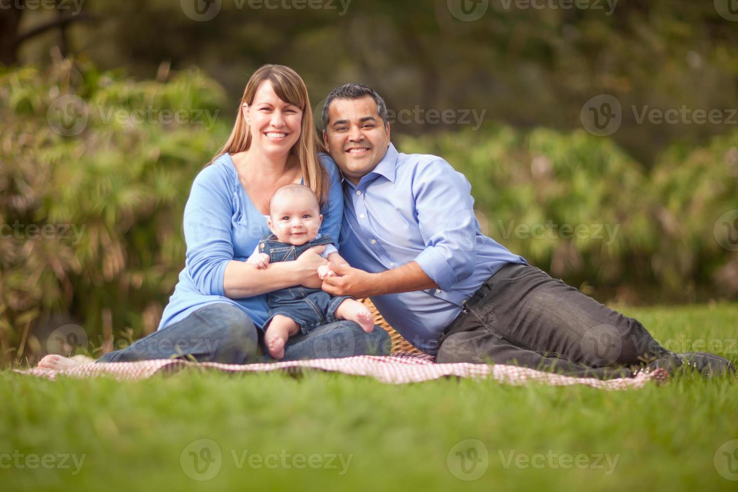 heureuse famille métisse ayant un pique-nique et jouant dans le parc photo