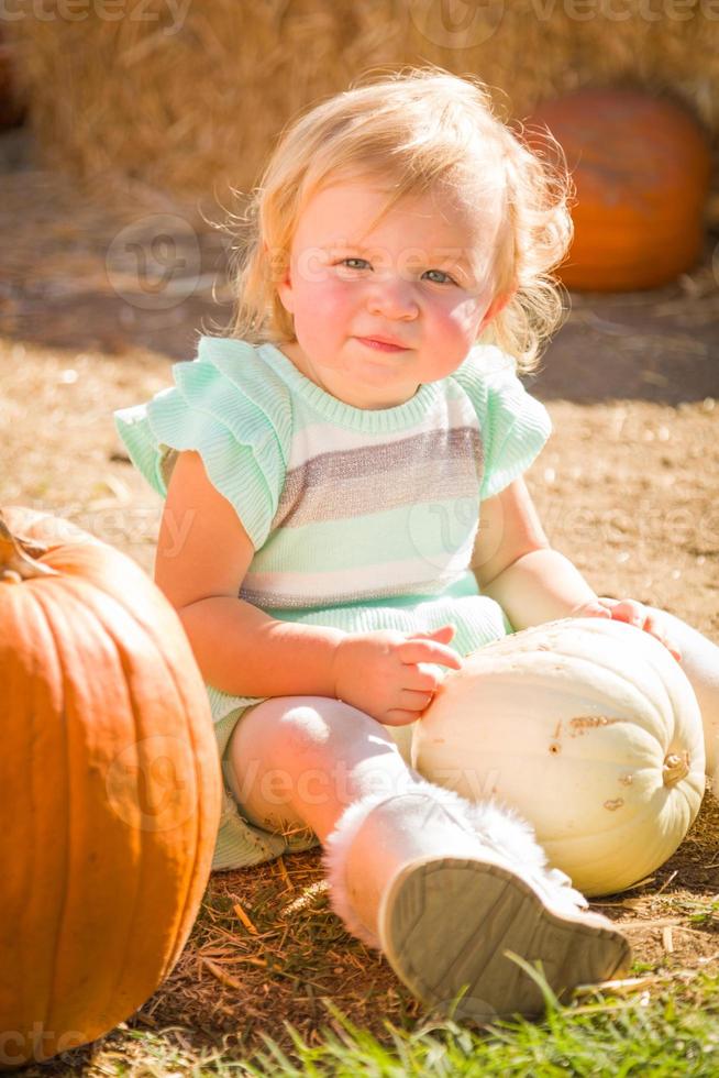 adorable petite fille s'amusant dans un ranch rustique au champ de citrouilles. photo