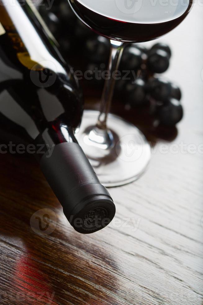 bouteille de vin abstraite, verre et raisins sur une surface en bois réfléchissante. photo