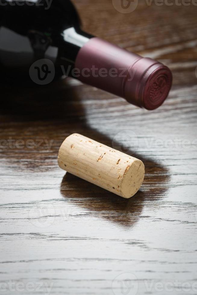 bouteille de vin et liège sur un résumé de surface en bois réfléchissant. photo