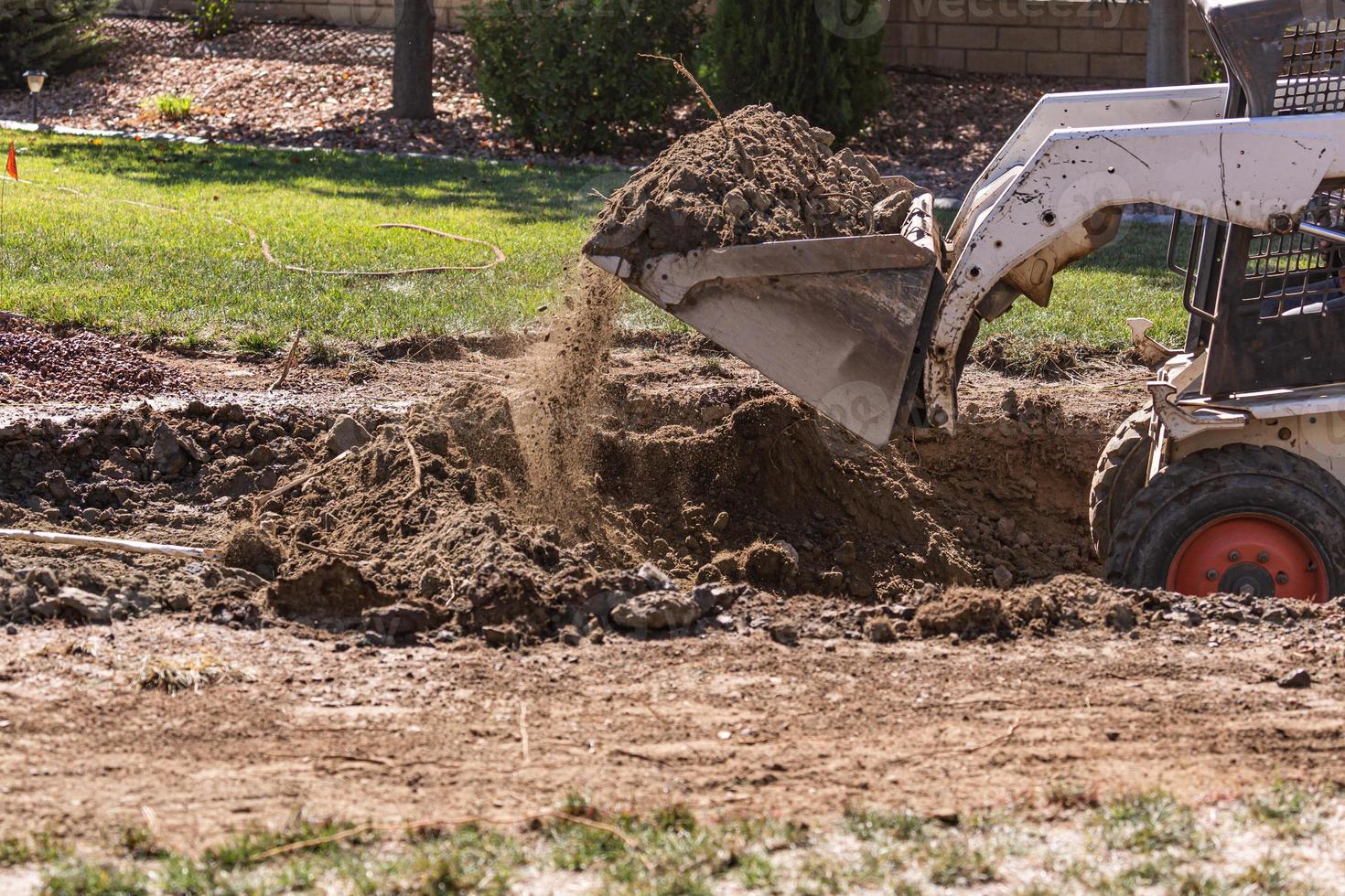 petit bulldozer creusant dans la cour pour l'installation de la piscine photo