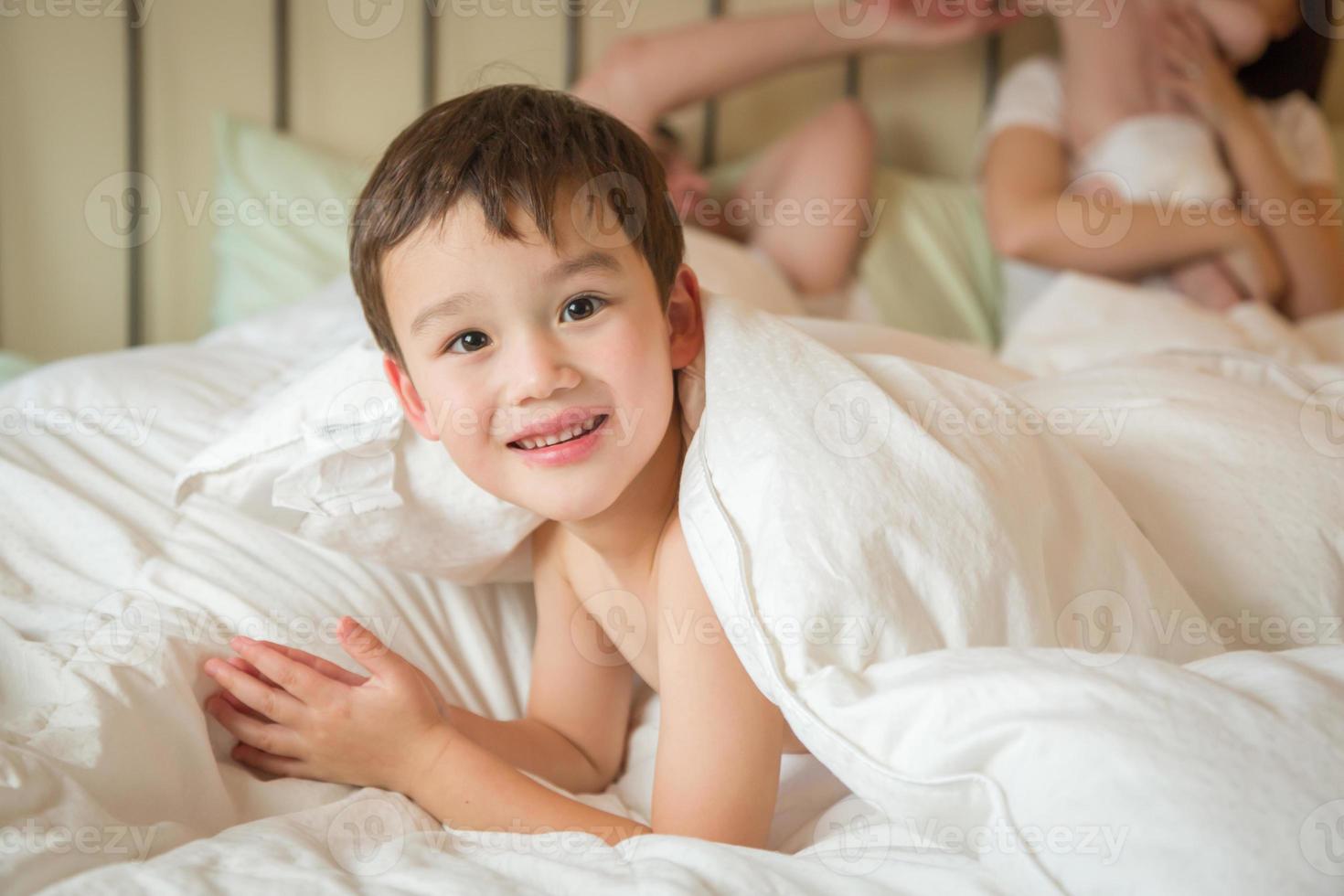garçon chinois et caucasien de race mixte allongé dans son lit avec son père et sa mère photo