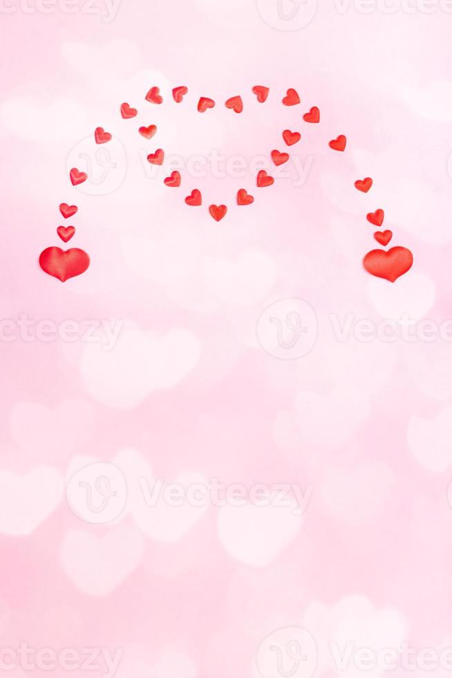 saint valentin ou mariage fond rose festif vertical avec coeurs bokeh. deux petits coeurs fusionnant en un seul grand coeur. photo