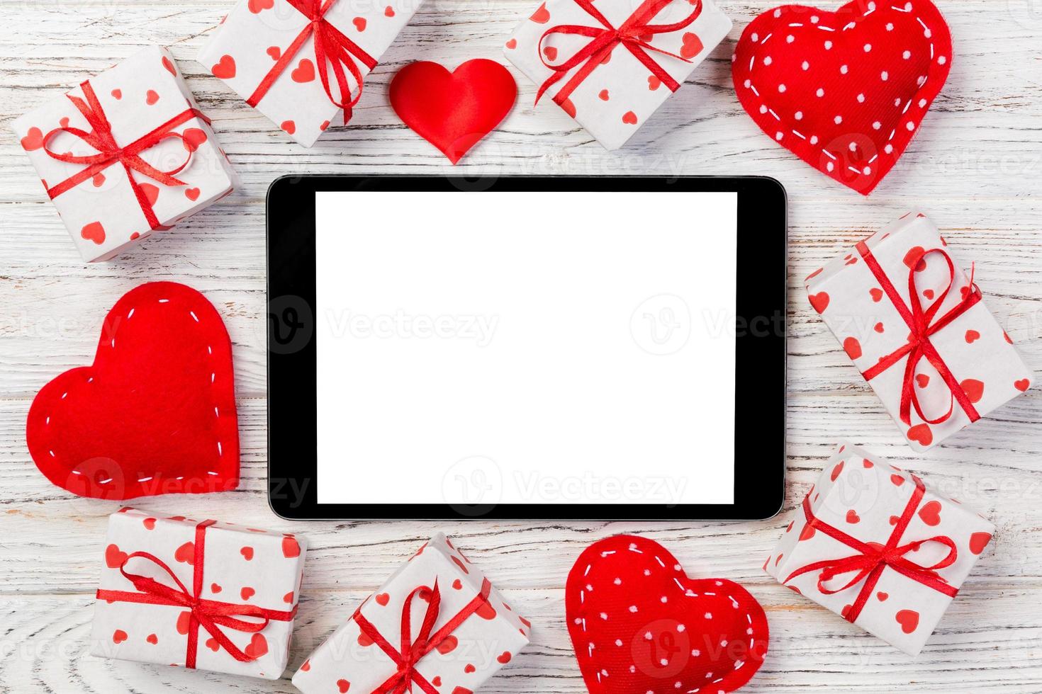 écran vide de tablette numérique avec boîte-cadeau et décor de coeurs sur table en bois. vue de dessus. fond de concept de saint valentin photo