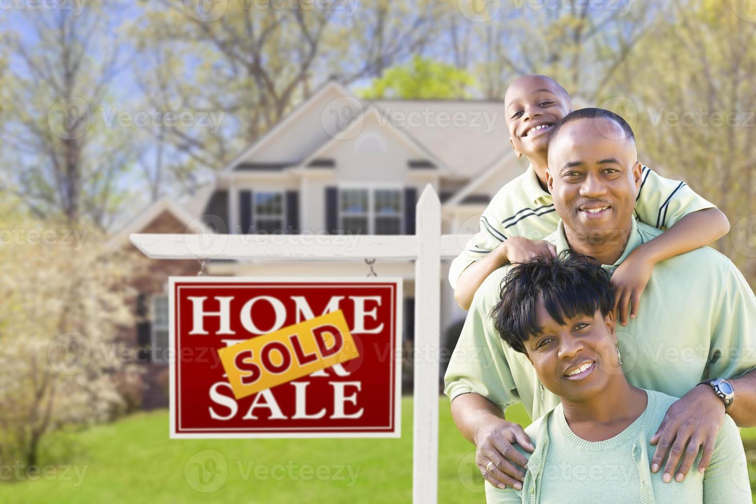 famille afro-américaine devant l'enseigne et la maison vendues photo