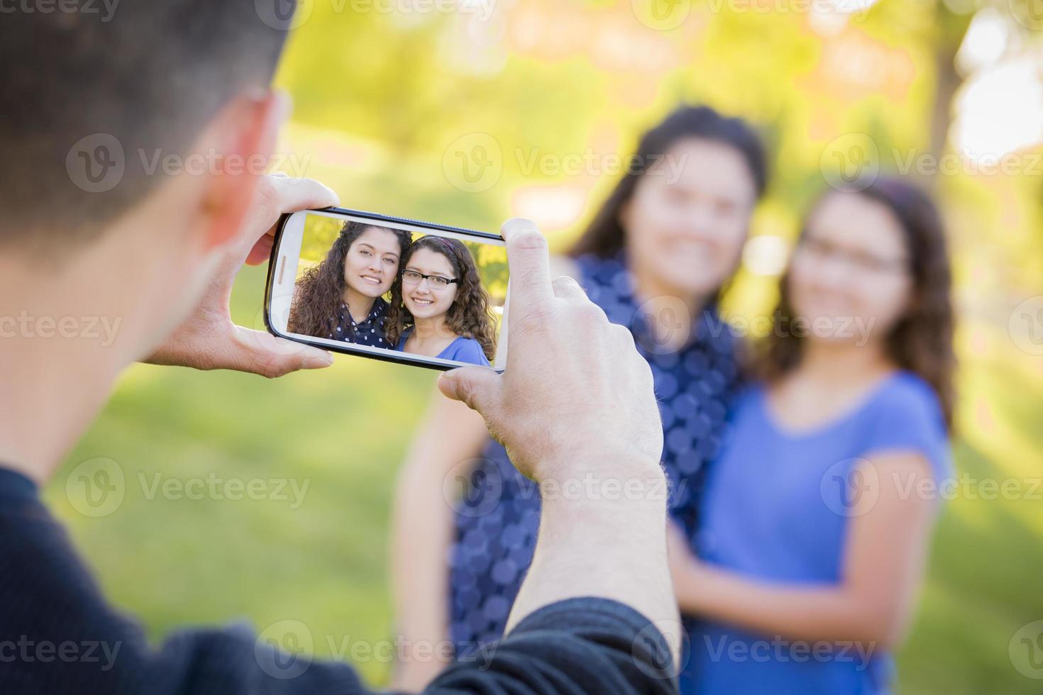 un homme prend une photo de sa femme et de sa fille sur son téléphone portable