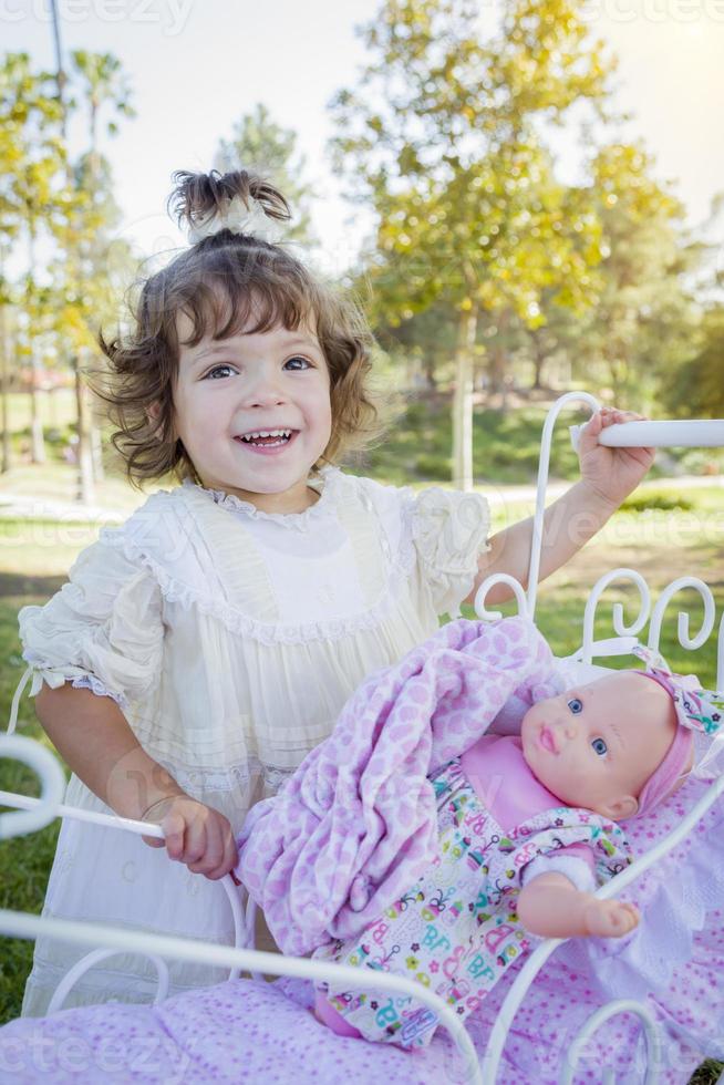 adorable jeune fille jouant avec une poupée et un chariot photo