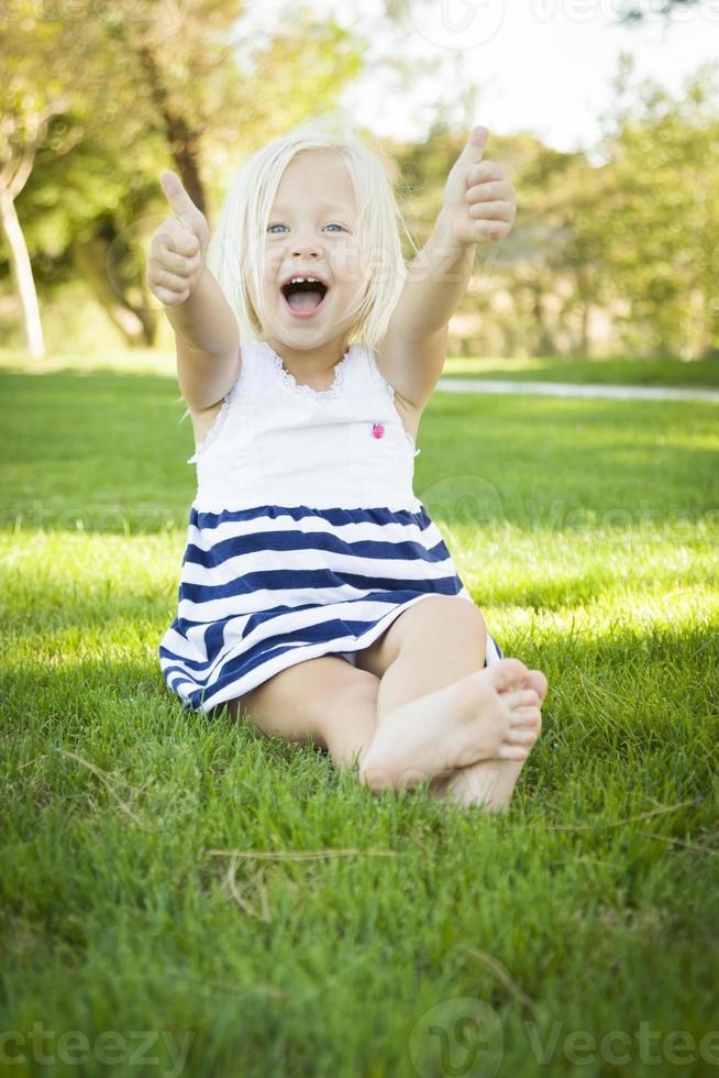 jolie petite fille avec les pouces vers le haut dans l'herbe photo