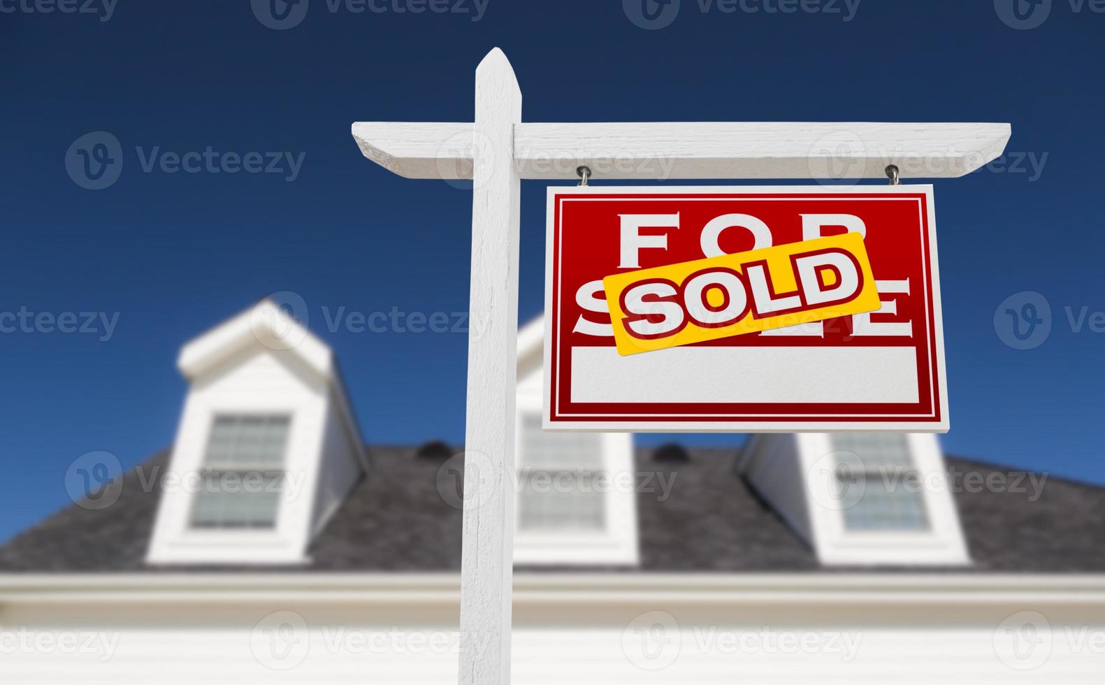face à droite vendu à vendre enseigne immobilière devant la maison et ciel bleu profond. photo