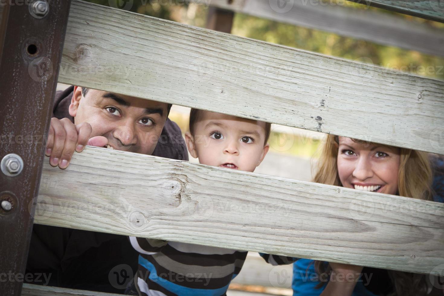 heureux jeune famille ethnique métisse regardant à travers une clôture photo
