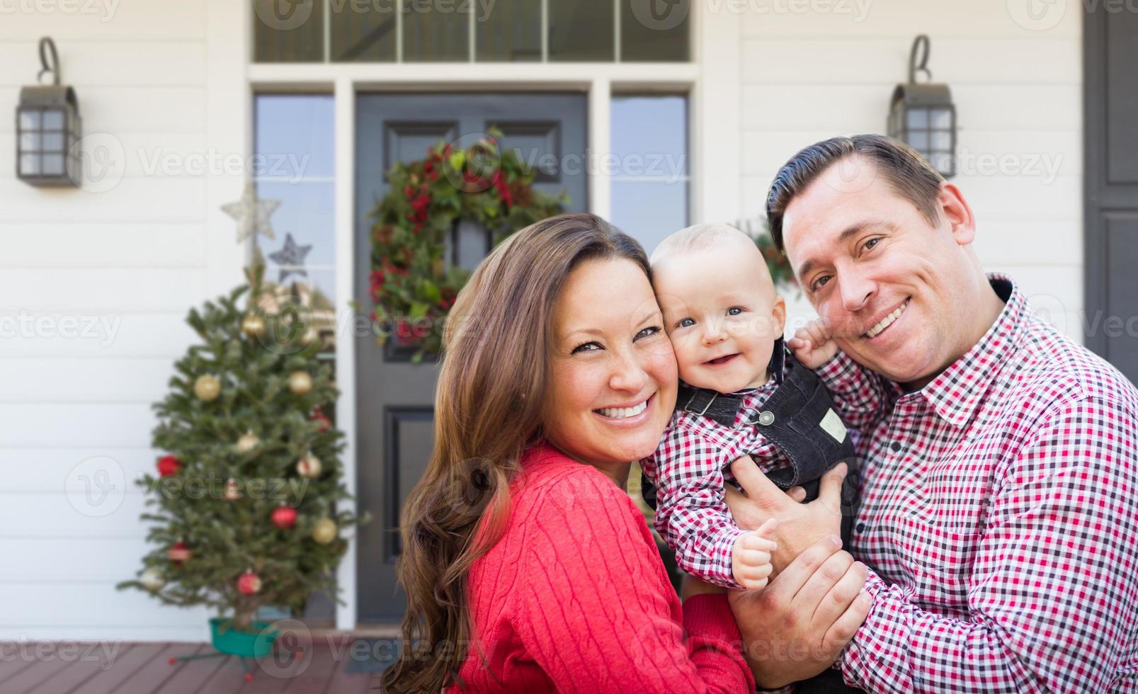 jeune famille heureuse sur le porche de la maison avec des décorations de Noël photo