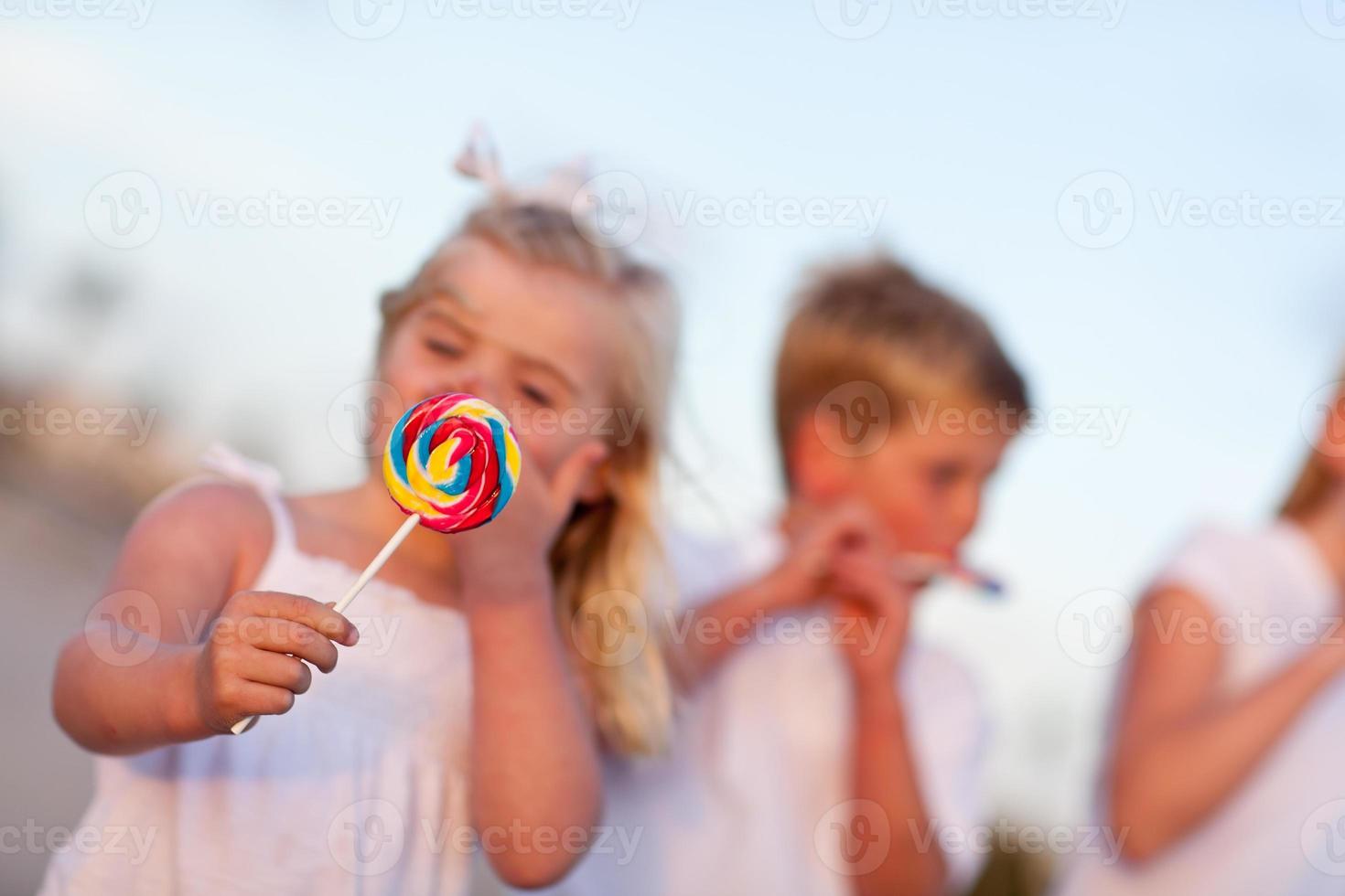 mignon frère et sœurs appréciant leurs sucettes à l'extérieur photo