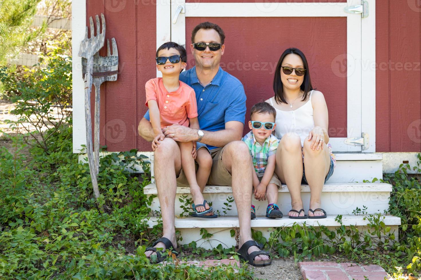 portrait d'un couple caucasien et chinois avec leurs jeunes garçons métis portant des lunettes de soleil photo