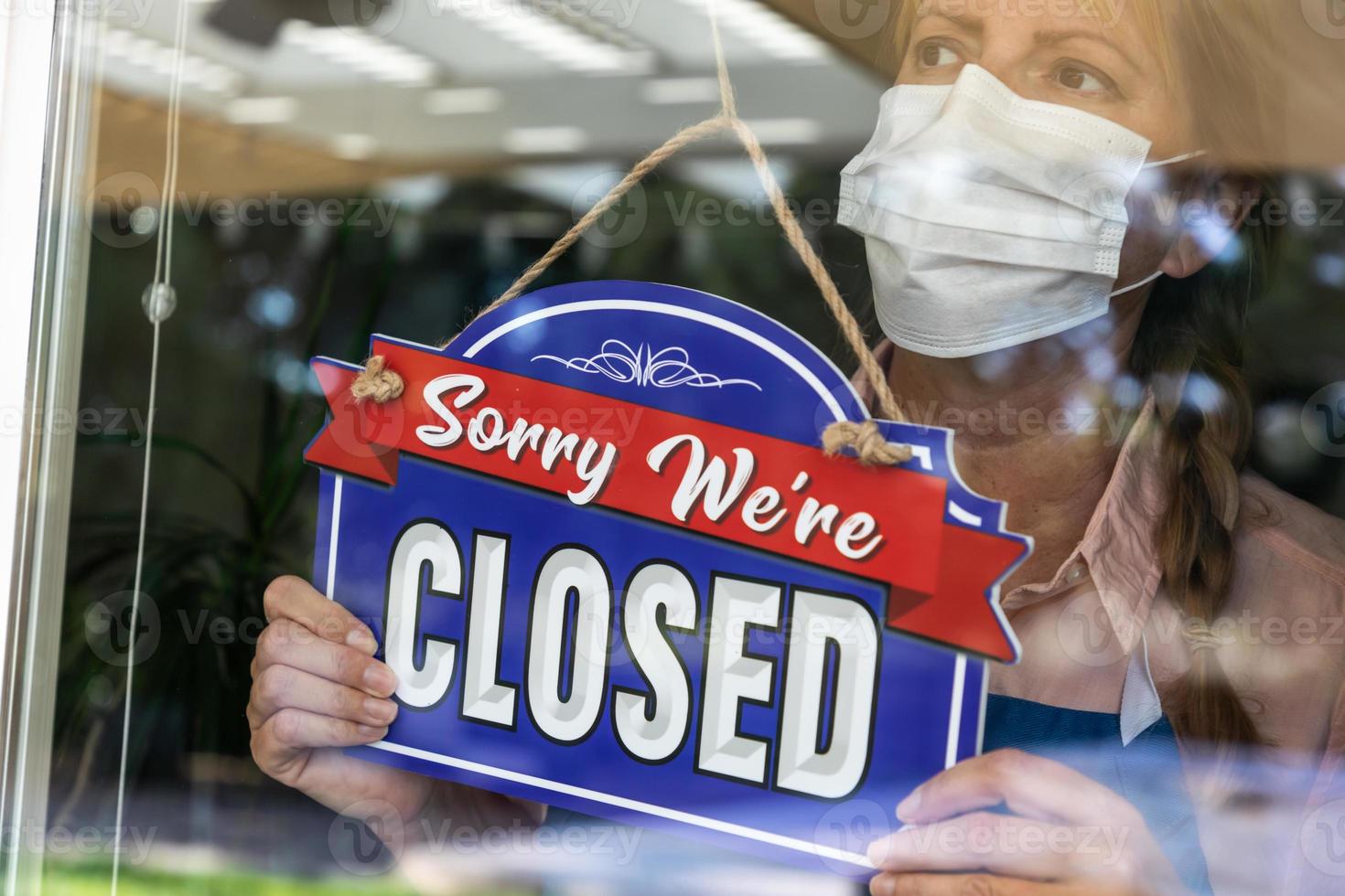 femme propriétaire d'un magasin portant un masque médical tournant le signe pour fermer la fenêtre photo