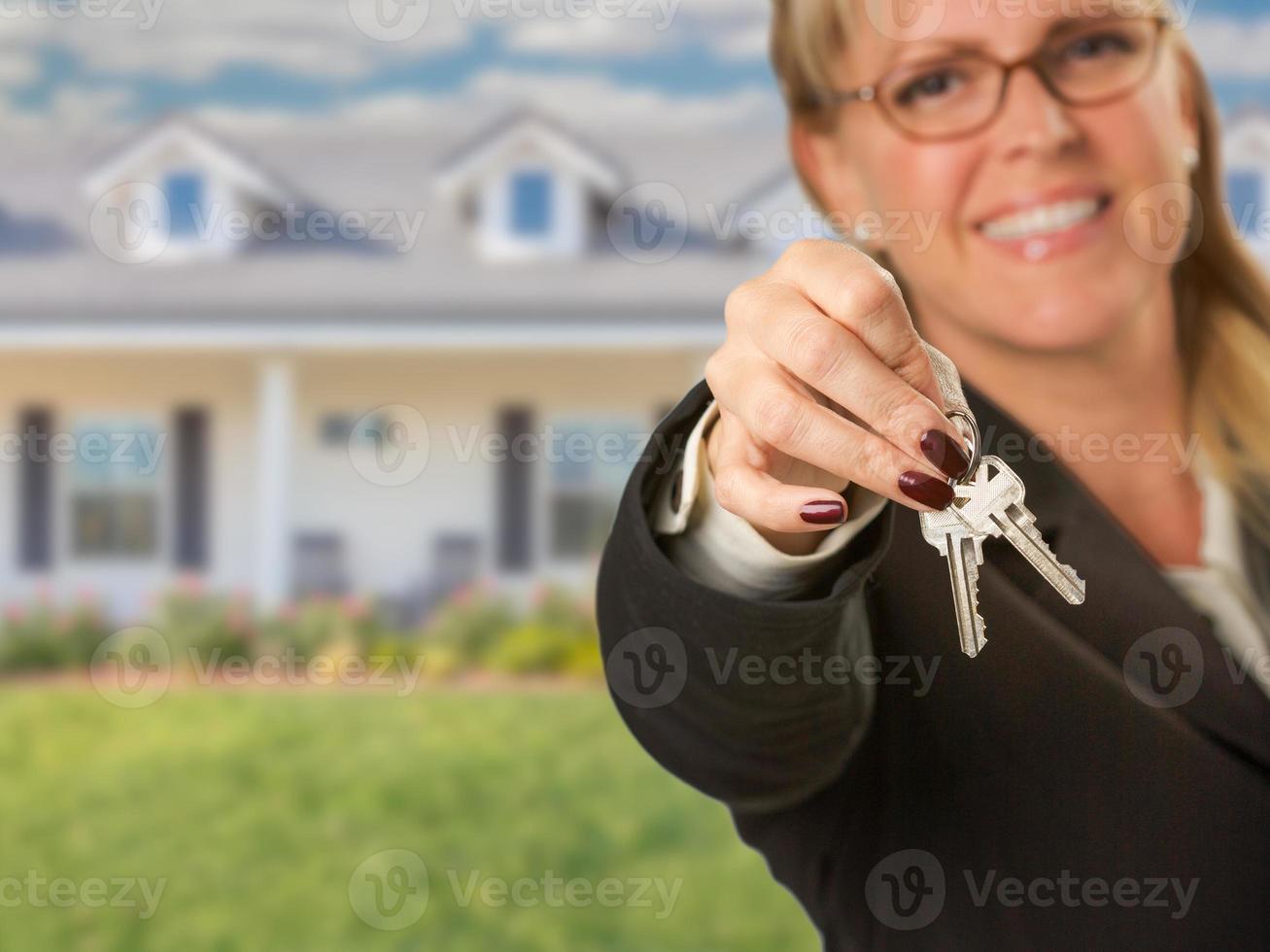 agent immobilier remettant de nouvelles clés de maison avec maison derrière photo