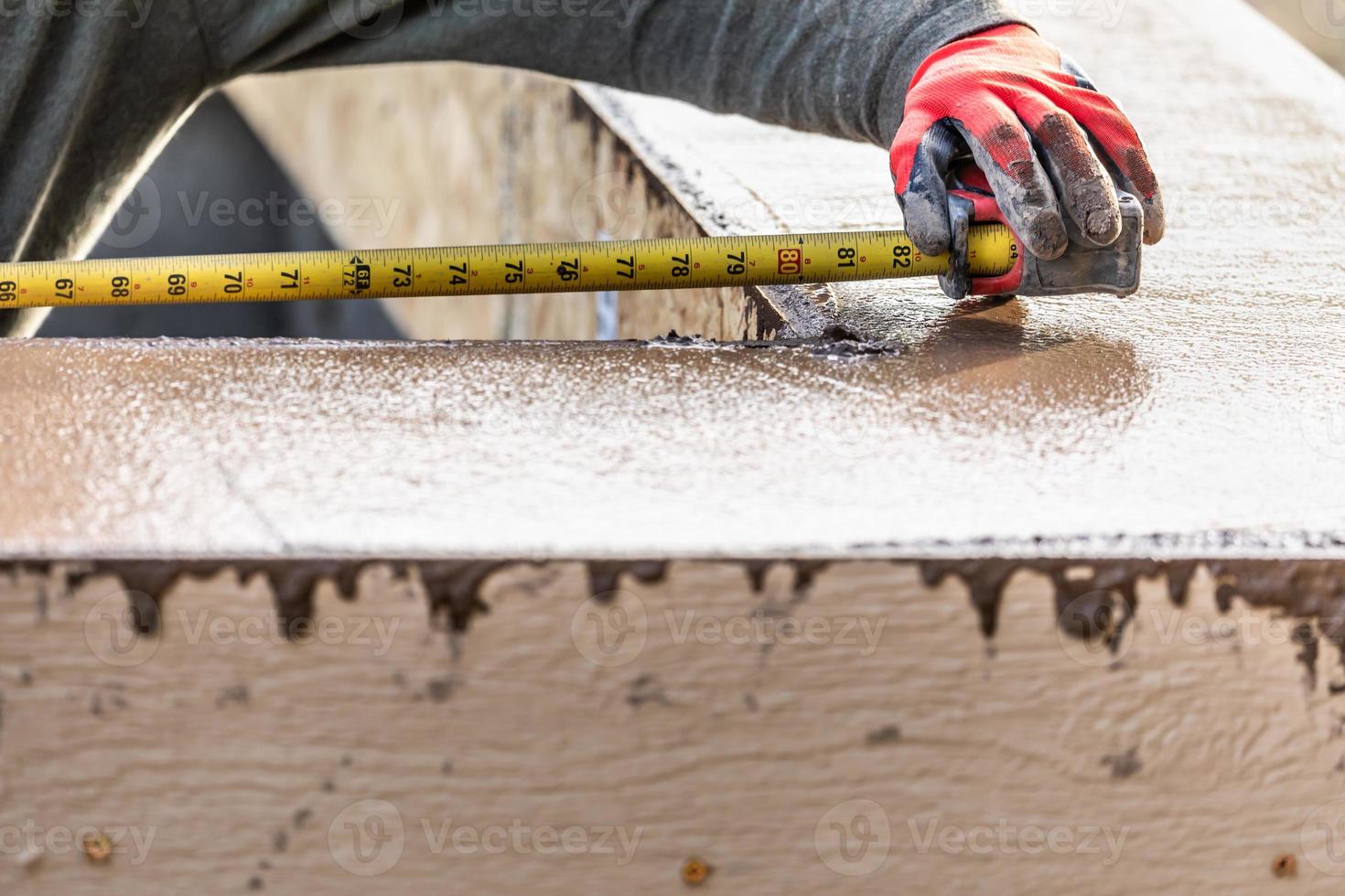 travailleur de la construction de ciment à l'aide d'un ruban à mesurer tout en formant une margelle de piscine photo