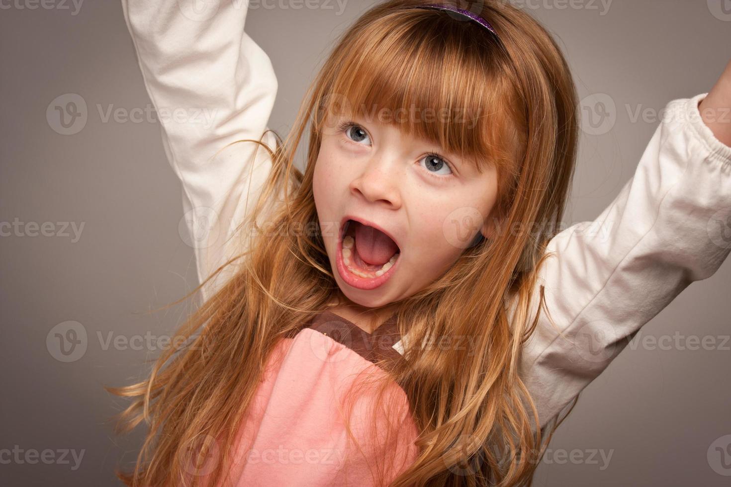 portrait amusant d'une adorable fille aux cheveux rouges sur gris photo