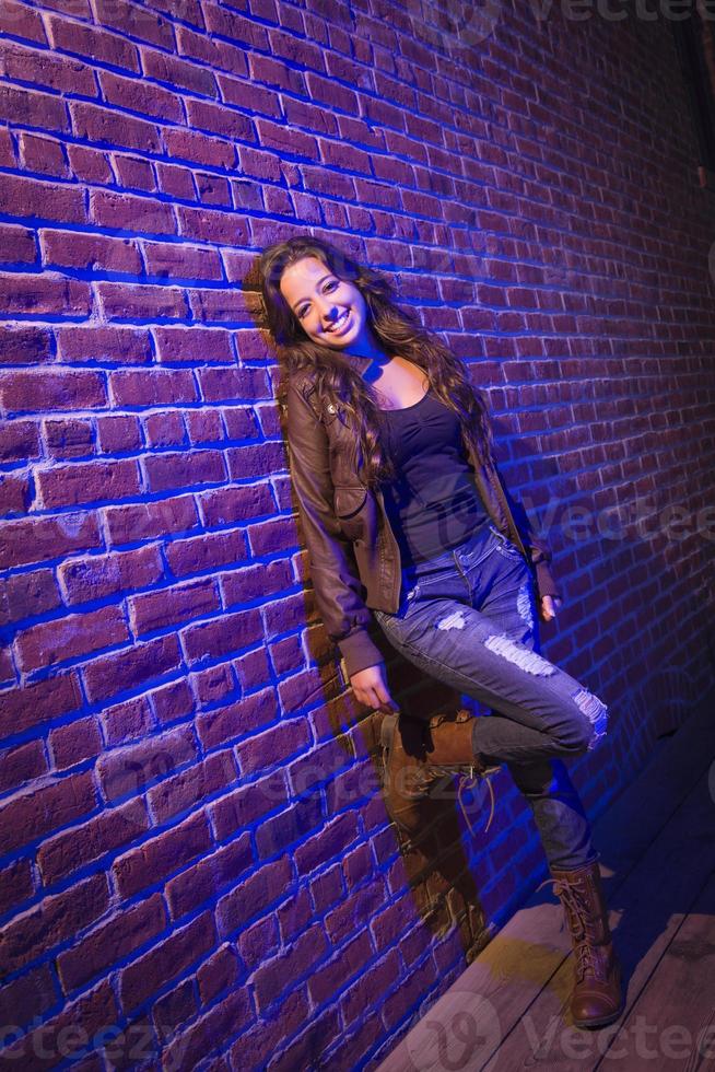 Jolie jeune femme adulte de race mixte contre un mur de briques photo