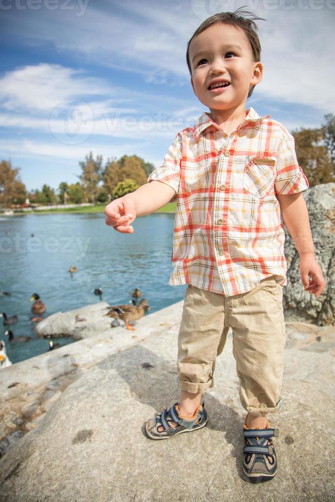 jeune garçon chinois et caucasien s'amusant au parc et à la mare aux canards. photo