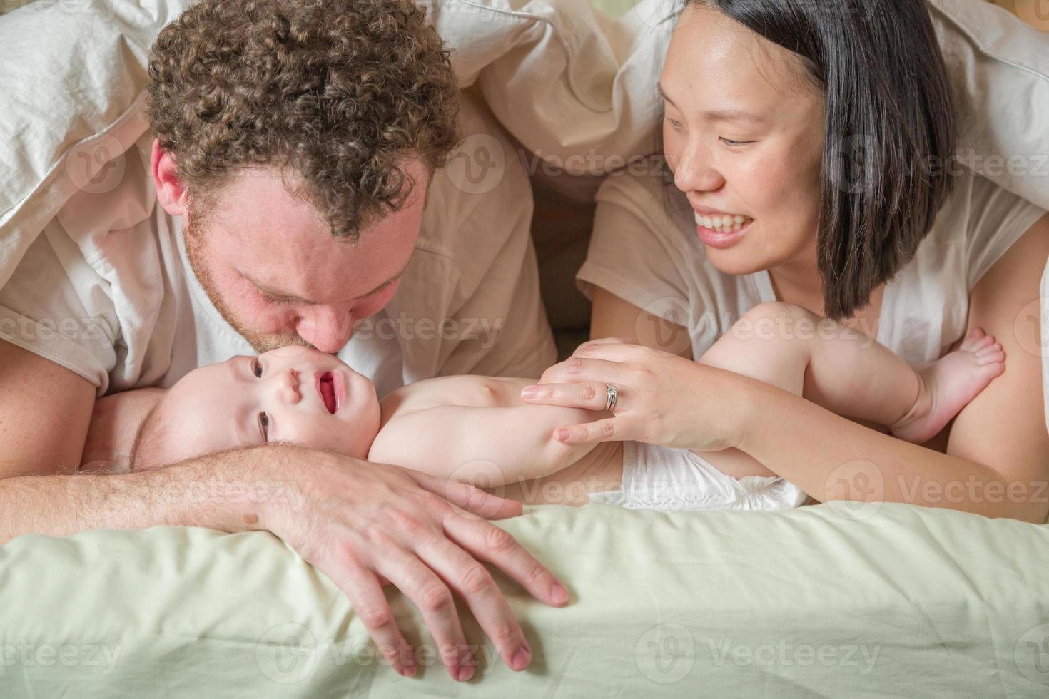 Mixed Race Chinese and Caucasian baby boy allongé dans son lit avec ses parents photo