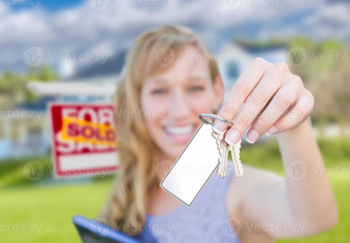 femme tenant de nouvelles clés de maison avec une carte vierge devant le signe de l'immobilier vendu et la maison. photo