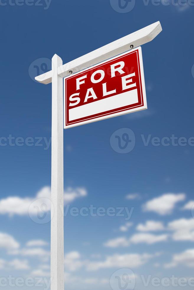 face à droite à vendre signe immobilier sur un ciel bleu avec des nuages. photo