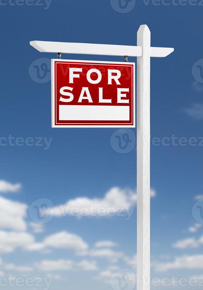face à gauche à vendre signe immobilier sur un ciel bleu avec des nuages. photo