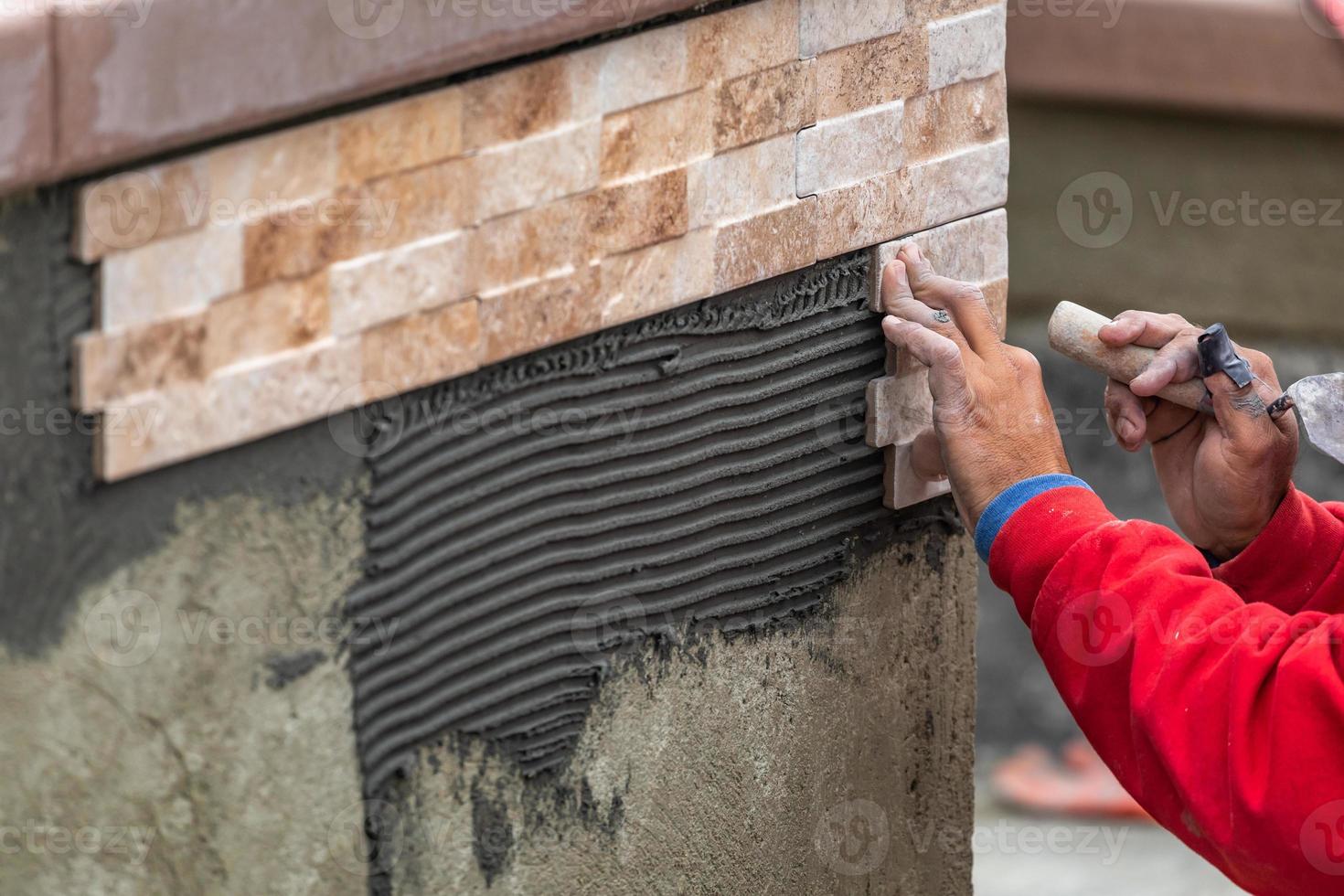 travailleur installant des carreaux de mur sur un chantier de construction photo