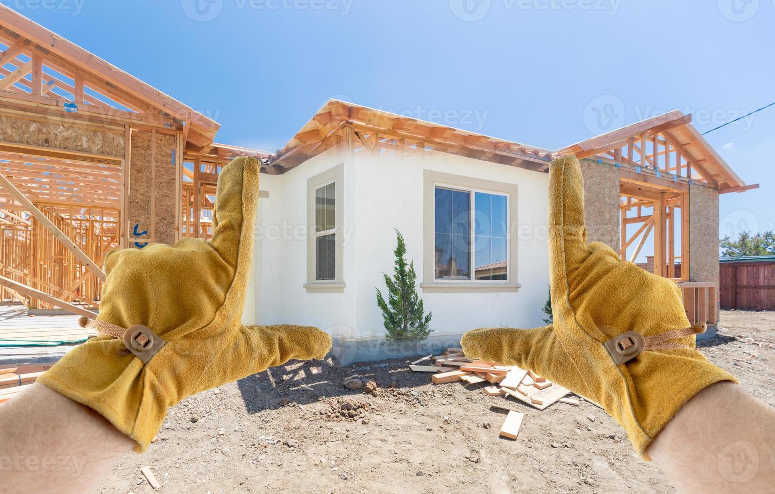 entrepreneur masculin mains encadrant la section terminée de la maison en cours de construction photo
