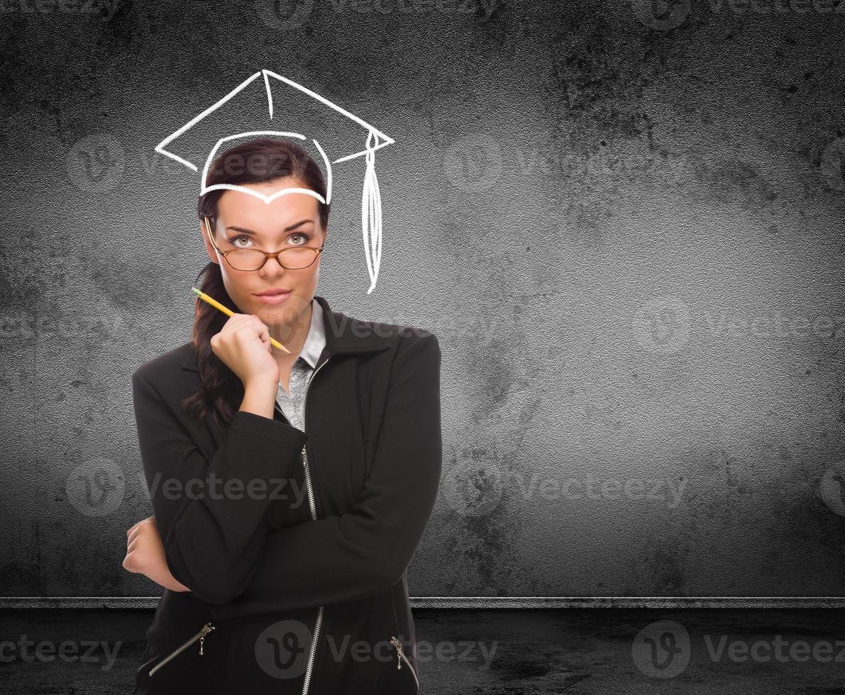 chapeau de graduation dessiné sur la tête d'une jeune femme adulte avec un crayon devant le mur avec espace de copie photo