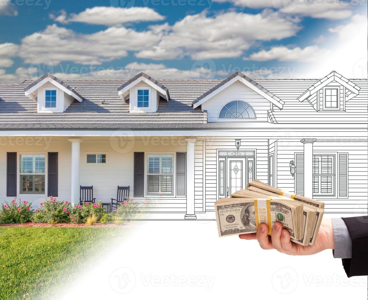 main tenant une pile d'argent sur le dessin de la maison passant à la photographie. photo