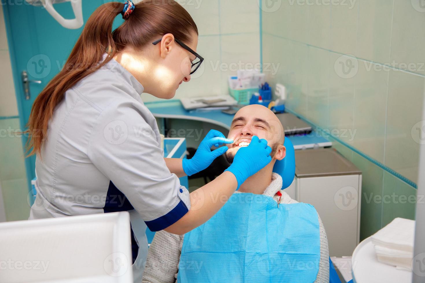 beau mec adulte sur la vérification des dents dans un cabinet dentaire photo