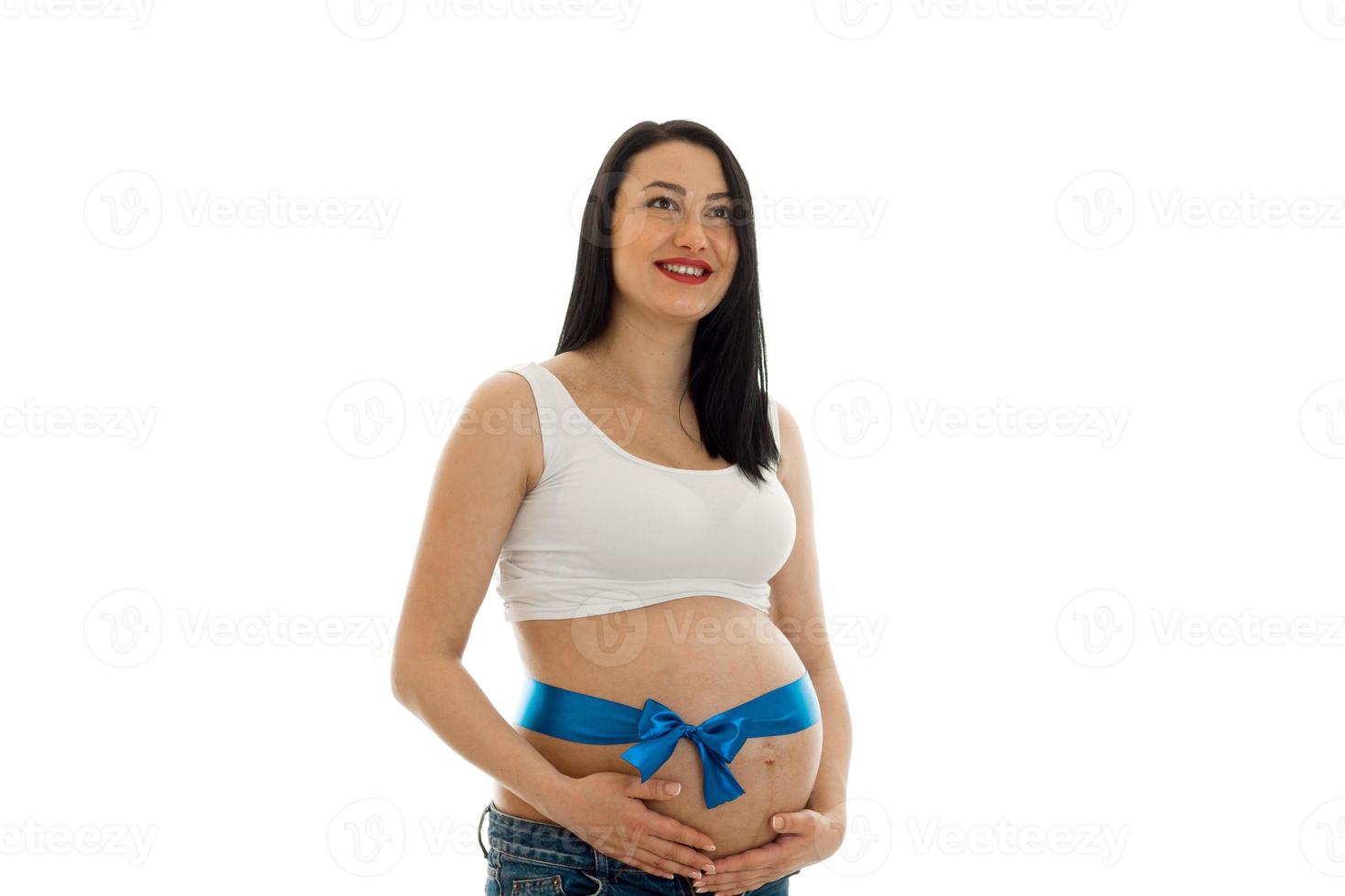 Jeune mère enceinte gaie avec ruban bleu sur le ventre isolé sur fond blanc en studio posant photo