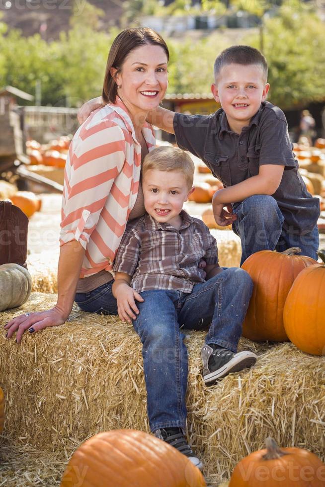 portrait d'une jolie mère et de ses fils au champ de citrouilles photo