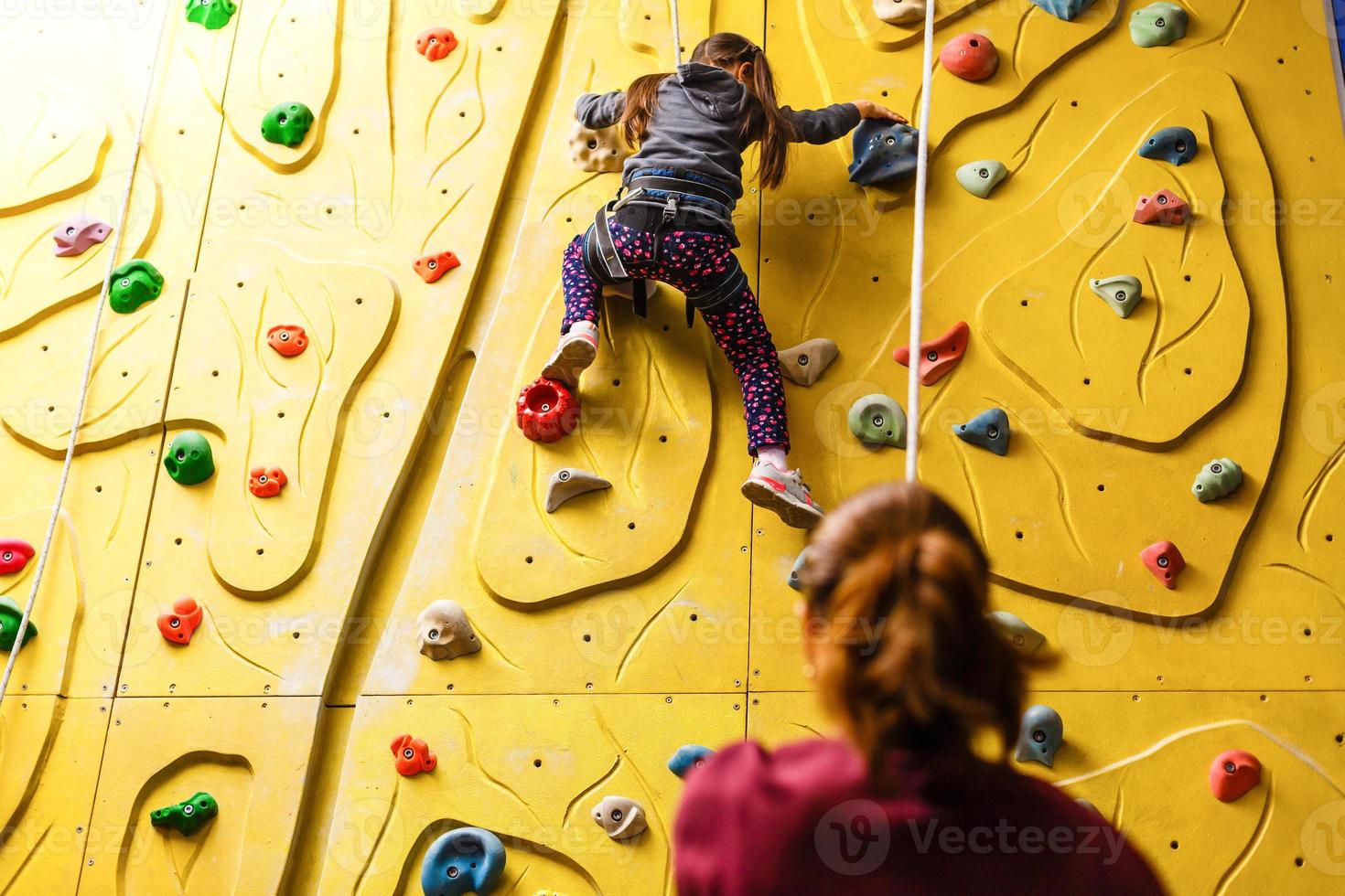 petite fille escaladant un mur de roche à l'intérieur photo