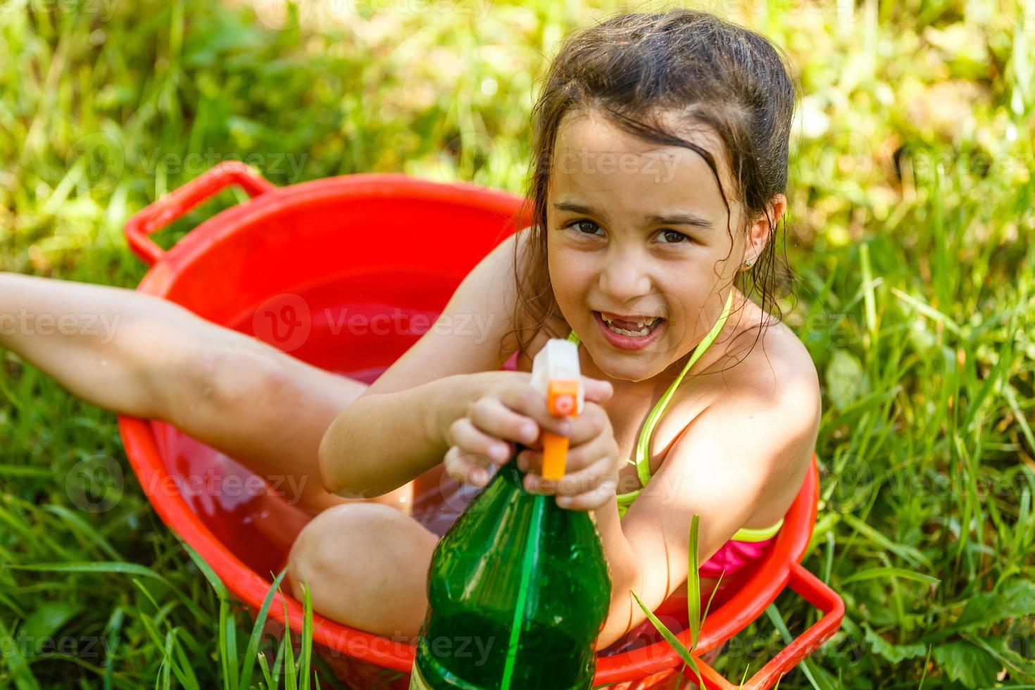 développement de l'enfant en harmonie avec la nature. petite belle fille s'amusant avec de l'eau et prenant un bain à l'extérieur sur l'herbe dans un bol à vaisselle vintage hygiène, enfance heureuse, concept nature photo