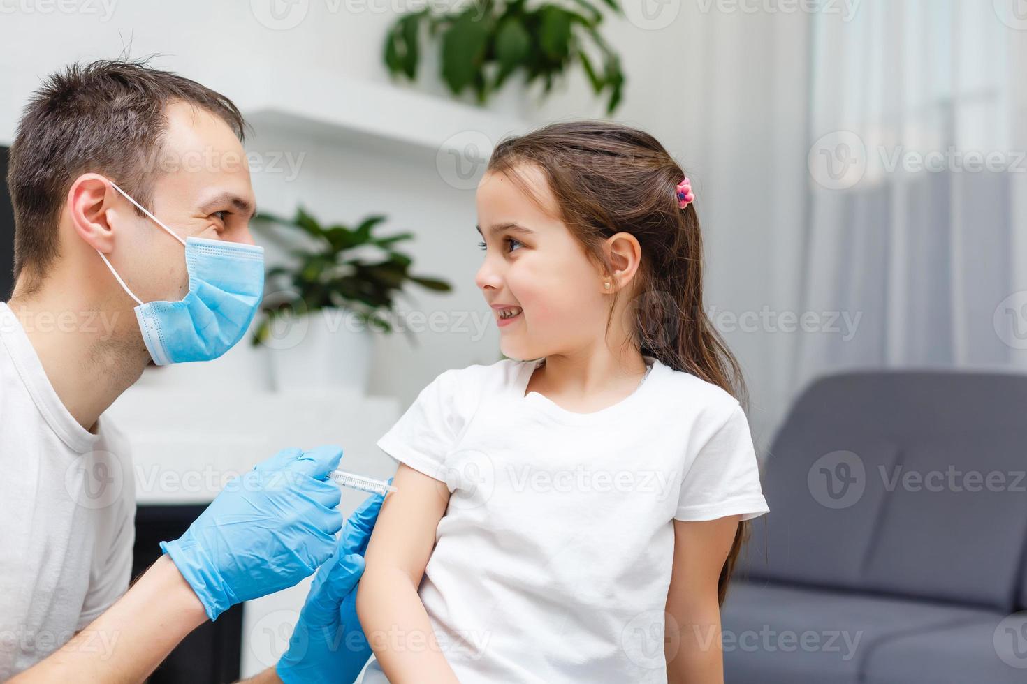 petite fille espiègle jouant à un jeu amusant en tant que médecin s'amusant avec son père assis sur un canapé, jolie petite fille faisant semblant d'infirmière en uniforme médical tenant un stéthoscope écoutant le père patient à la maison photo