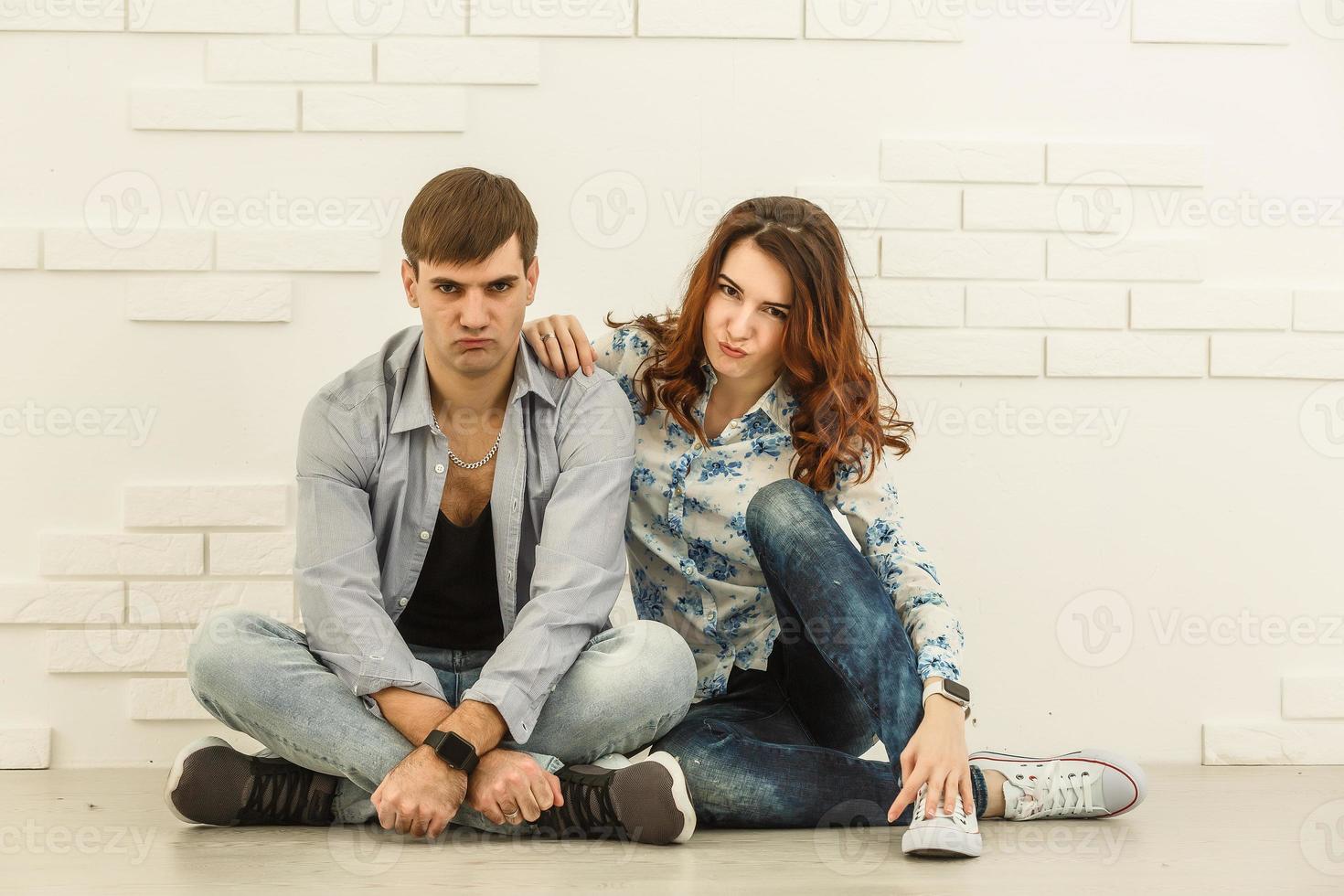 l'homme et la femme heureux s'assoient sur le fond du mur blanc photo