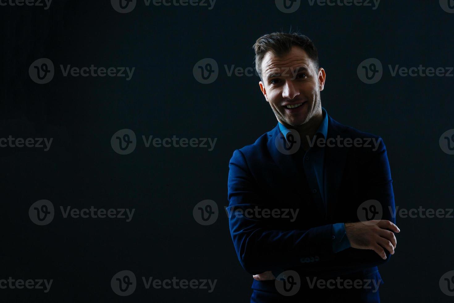 heureux homme d'affaires souriant avec les bras croisés sur fond noir photo