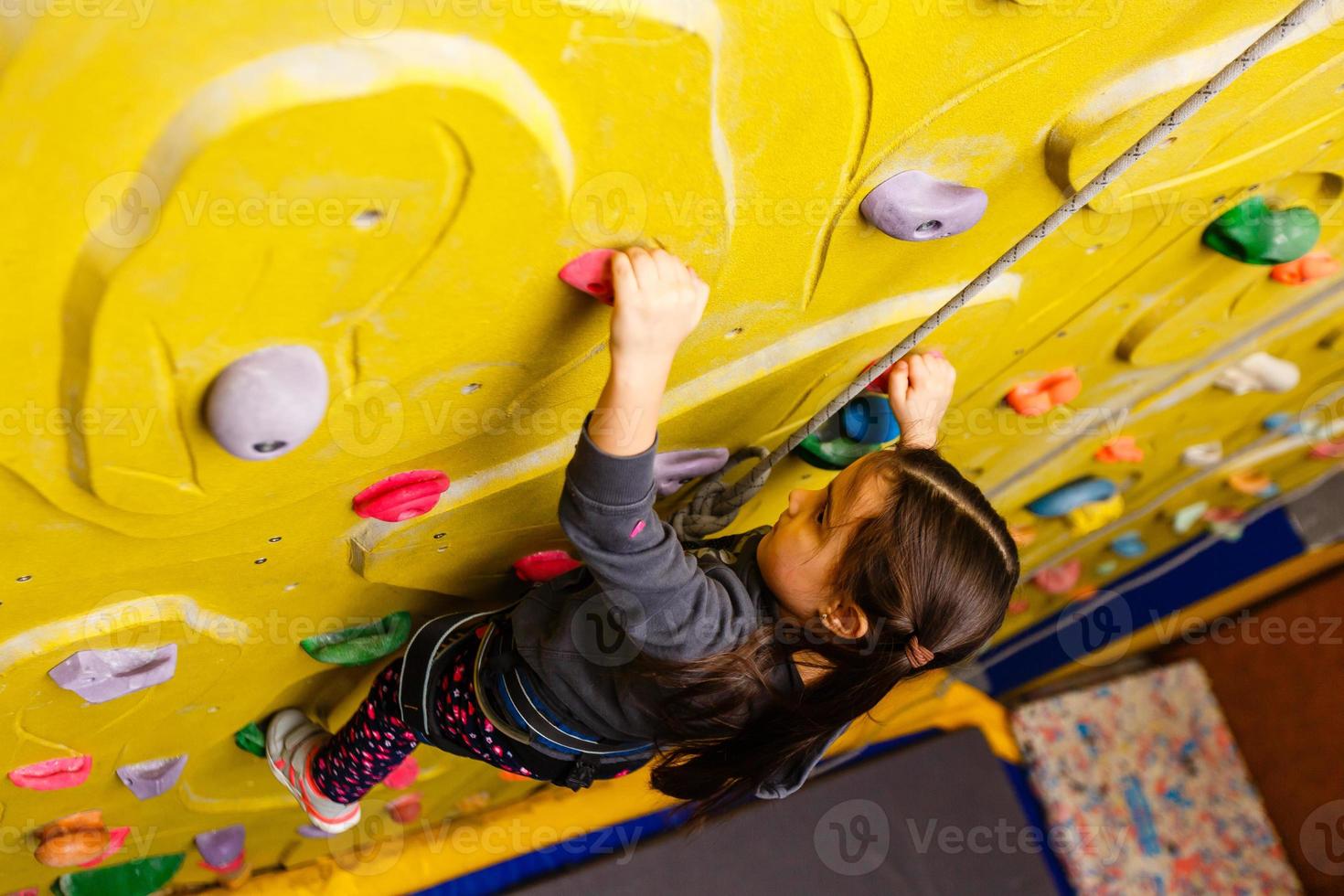 petite fille escaladant un mur de roche à l'intérieur. photo