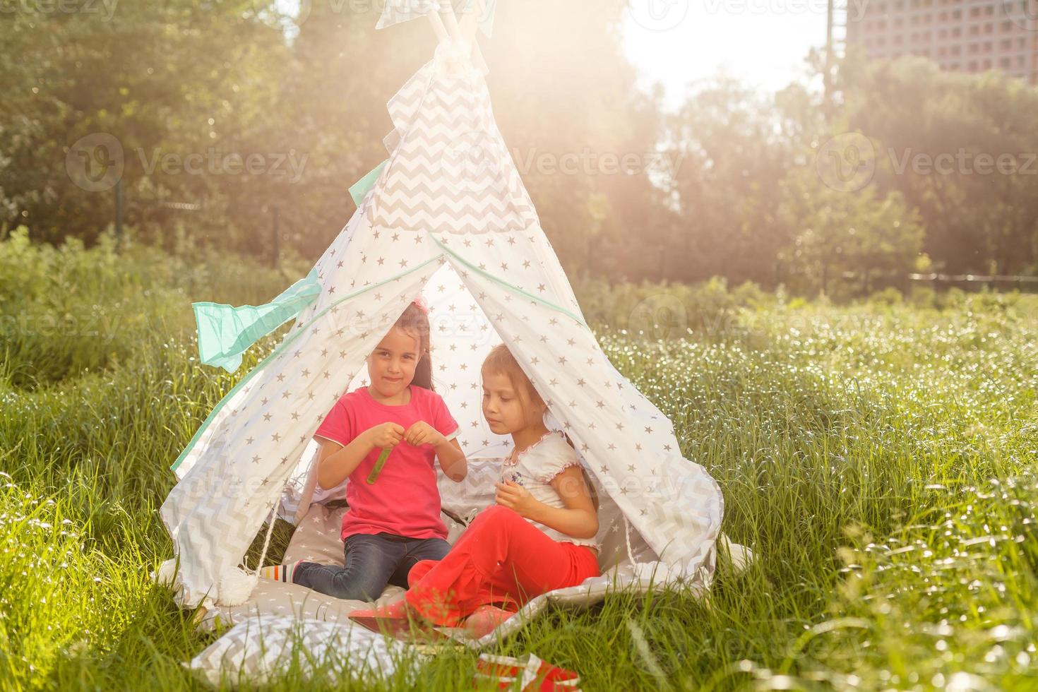 concept d'enfance et d'hygge - petites filles heureuses jouant dans une tente pour enfants photo