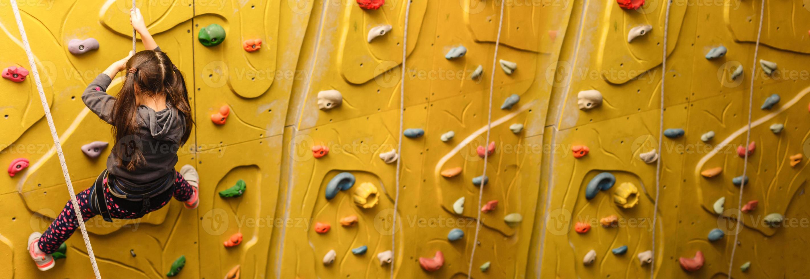 petite fille escaladant un mur de pierre photo