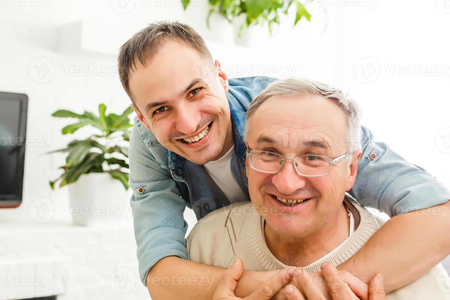 père senior avec son fils adulte se reposant sur un canapé à la maison photo