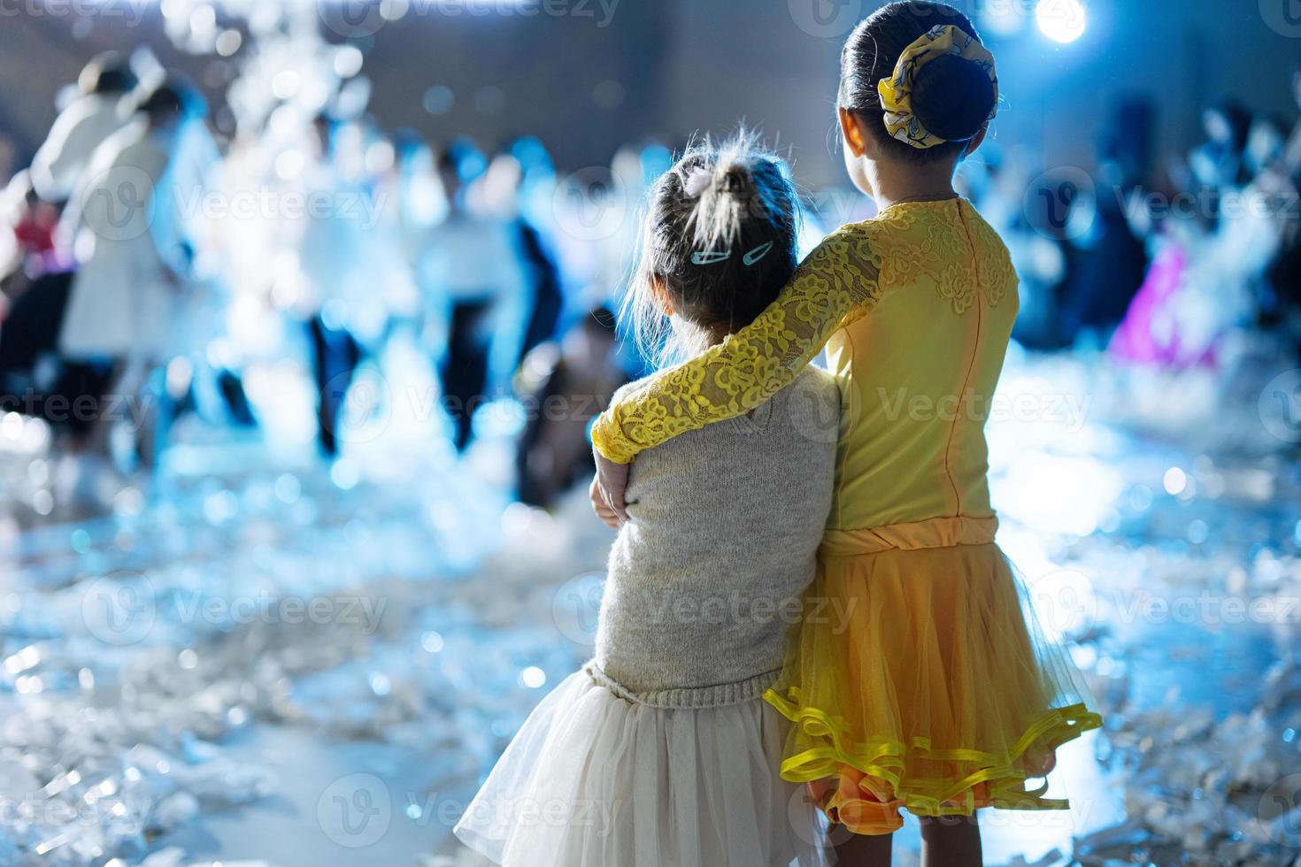 le dos de deux soeurs s'embrassent, portent une robe de costume de danse à la fête des enfants. photo