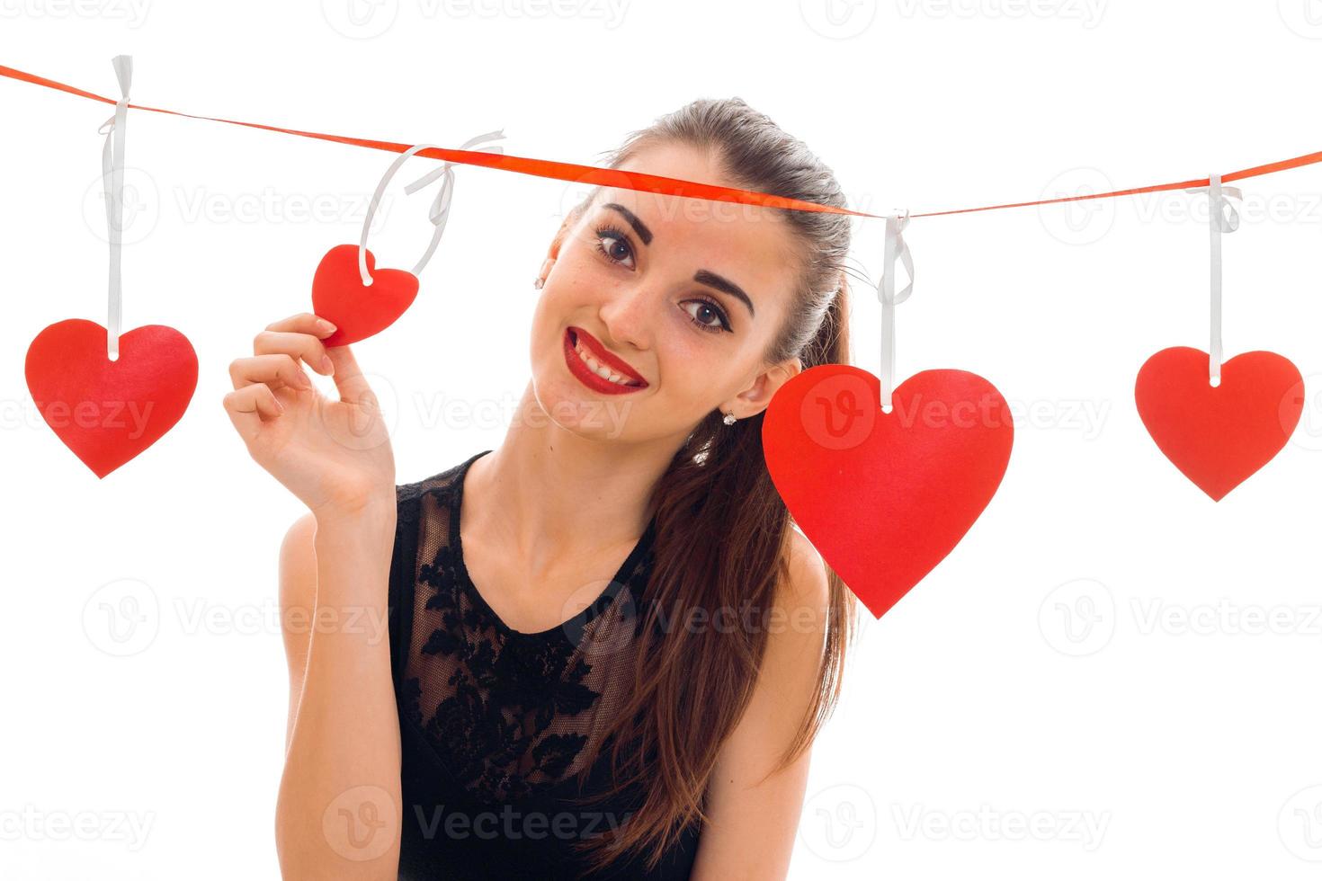 joyeuse jeune femme brune aux lèvres rouges et coeur en studio posant isolé sur fond blanc photo