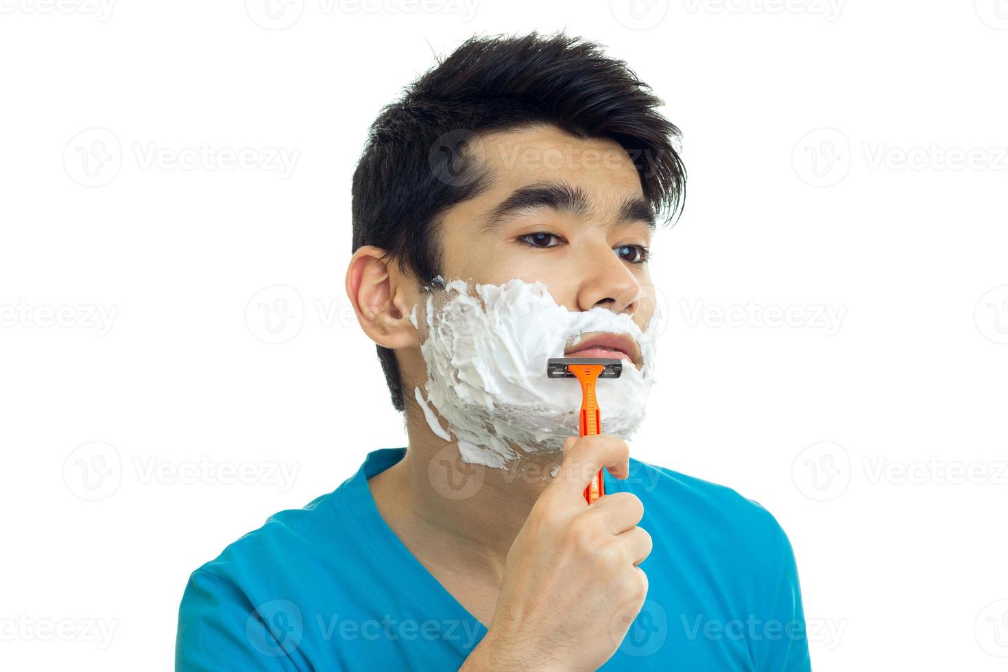 un portrait en gros plan du gars aux cheveux noirs et à l'écume sur le visage avec un rasoir photo